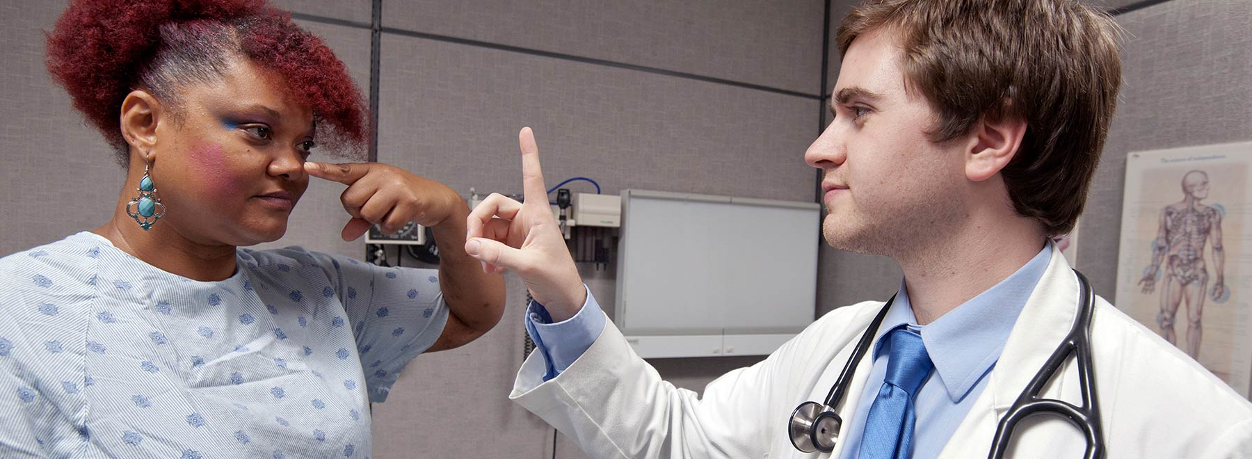 A patient actor with a student in a simulation lab